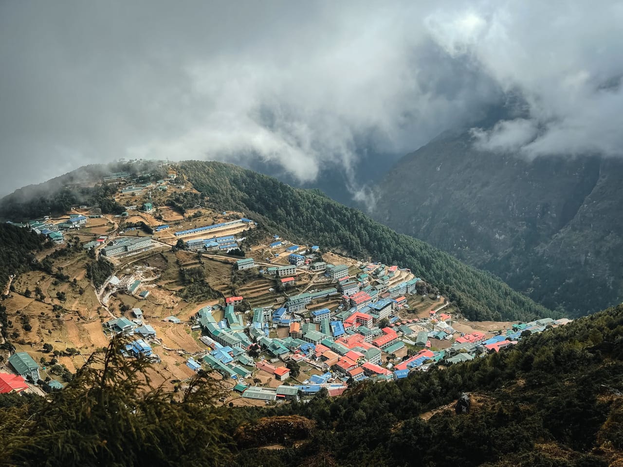 Namche Bazaar curved into its mountainside, lodges facing the peaks