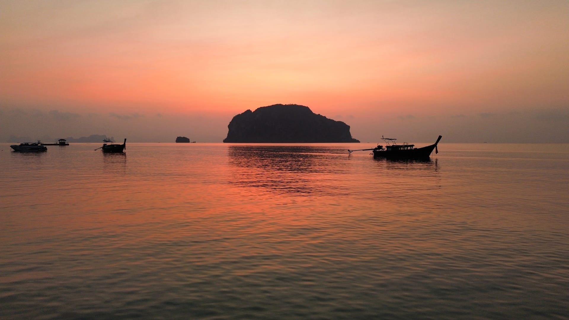 Longtail boats and islands in silhouette at sunrise on Phang Nga Bay