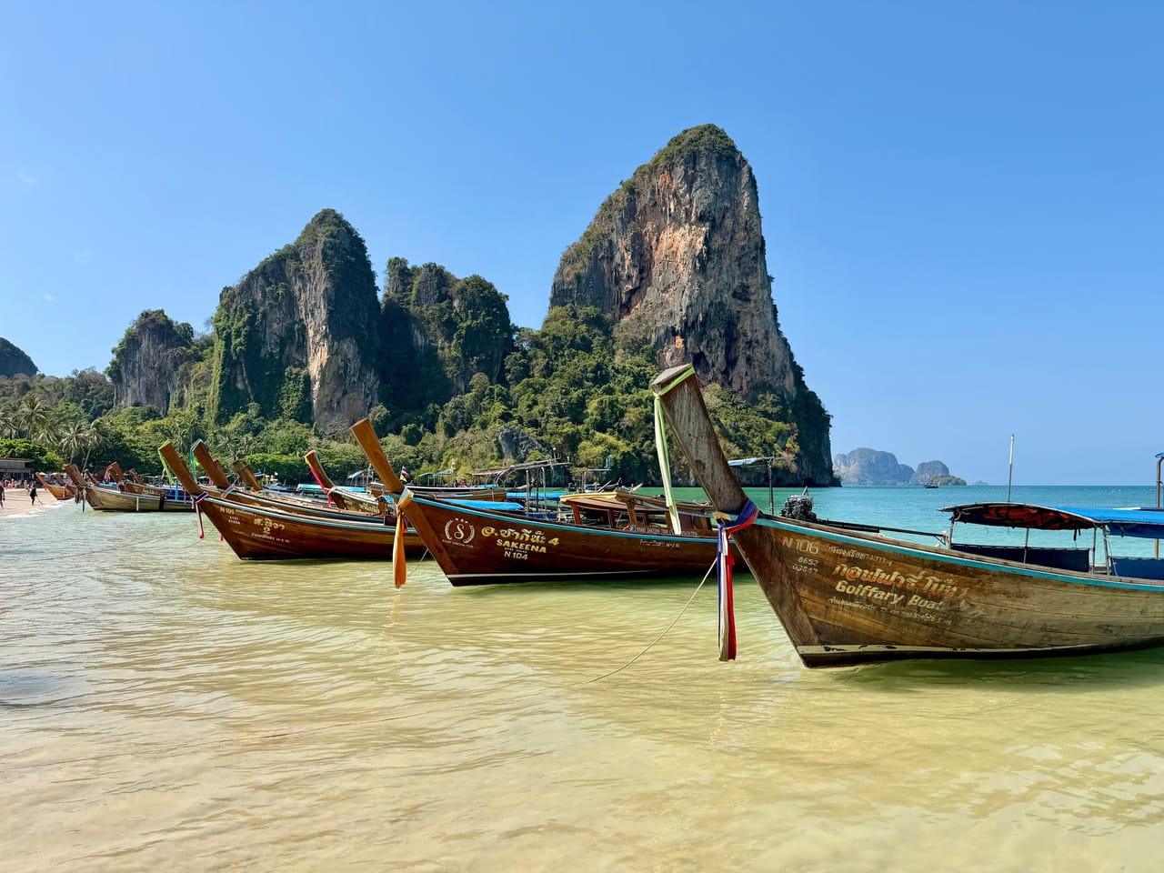 Longtail boats waiting in the shallows below the Railay cliffs