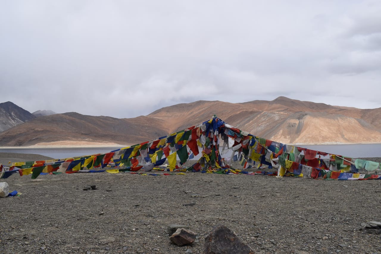 Prayer flags strung above the turquoise water of Yamdrok Tso