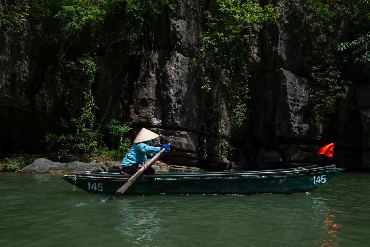 A sampan rowed between the karsts at Trang An, Ninh Binh